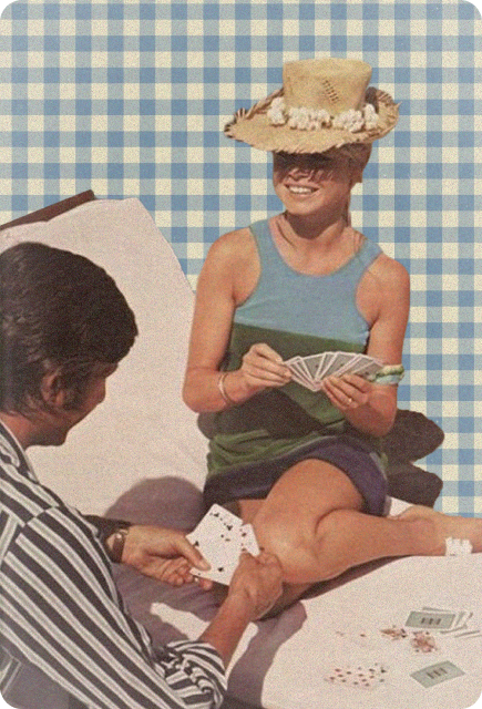 Two people relaxing outdoors while playing cards on a picnic blanket, representing simple picnic activities and conversation.