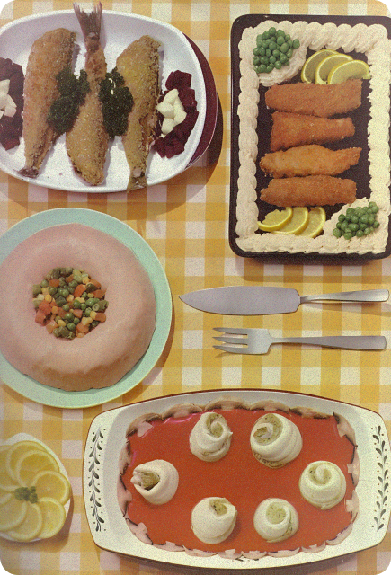Vintage-style picnic spread with sandwiches, vegetables, fish, and lemon garnishes arranged on a checkered tablecloth.