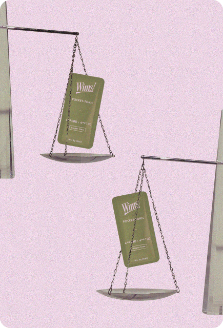 Two Wims Ginger Lime Pocket-Tonic packets displayed on hanging balance scales against a soft pink background, symbolizing a smooth, balanced buzz for mixology.