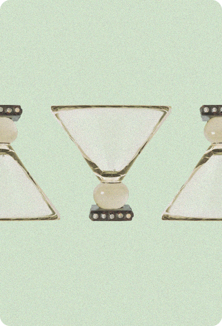 Three upside-down martini glasses aligned horizontally, each balanced on a small decorative base, set against a soft mint-green background.