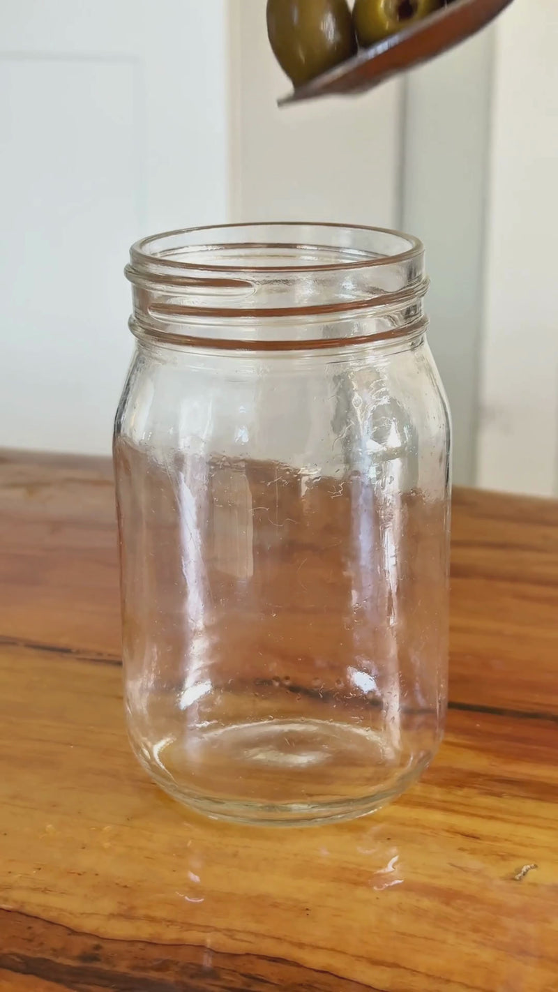 Green olives added to a glass jar with olive brine while a Wims Unflavored Pocket-Tonic™ is snapped in, then the jar is closed and gently mixed to marinate.