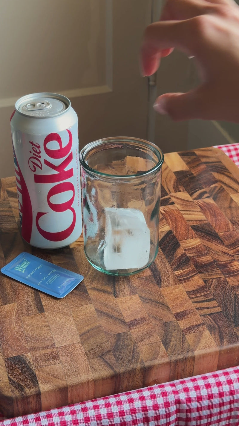 Diet Coke being poured over ice in a tall glass to make the Wims Fridge Cig.