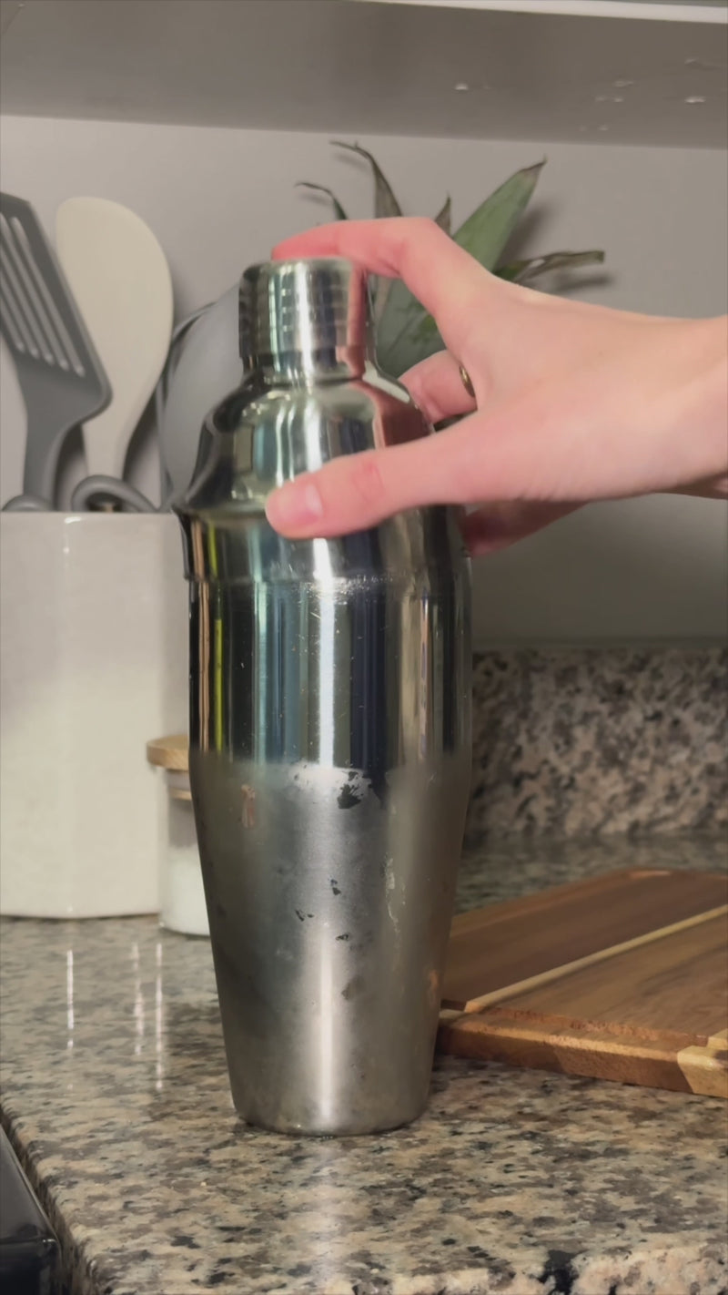 Cocktail shaker being shaken to chill the tropical pineapple and coconut mixture as fresh mint becomes fragrant.