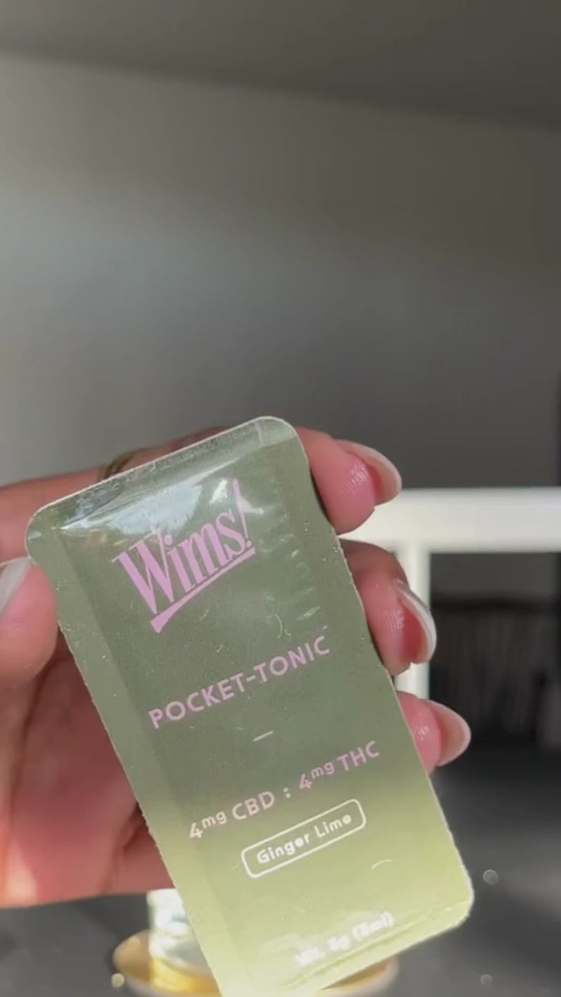 A Wims Ginger Lime Pocket-Tonic™ is snapped open and stirred into the fizzy drink. The glass is garnished with a few fresh blueberries, adding vibrant pops of blue against the light, bubbly beverage.