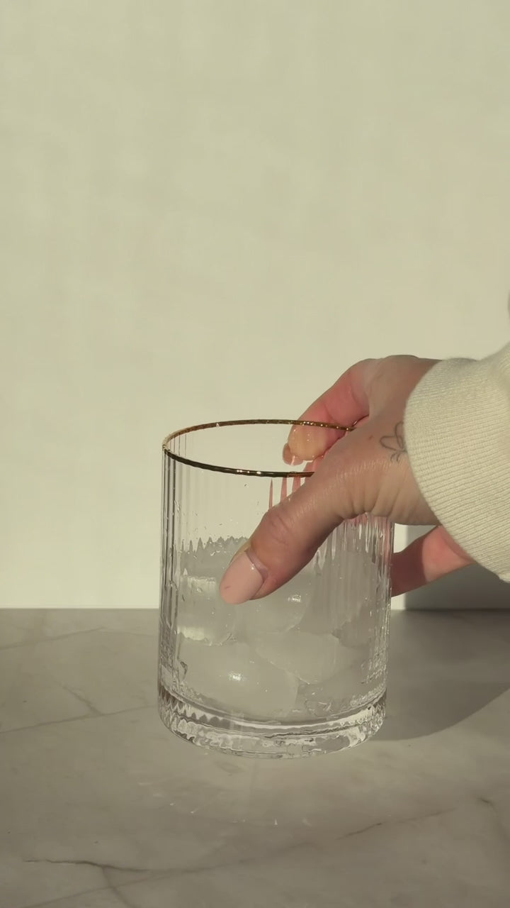 Hand adding cranberry-orange syrup to a glass filled with ice, snapping open and stirring in a Ginger Lime Wims Pocket-Tonic™, then topping with ginger ale and gently stirring to finish the mocktail.