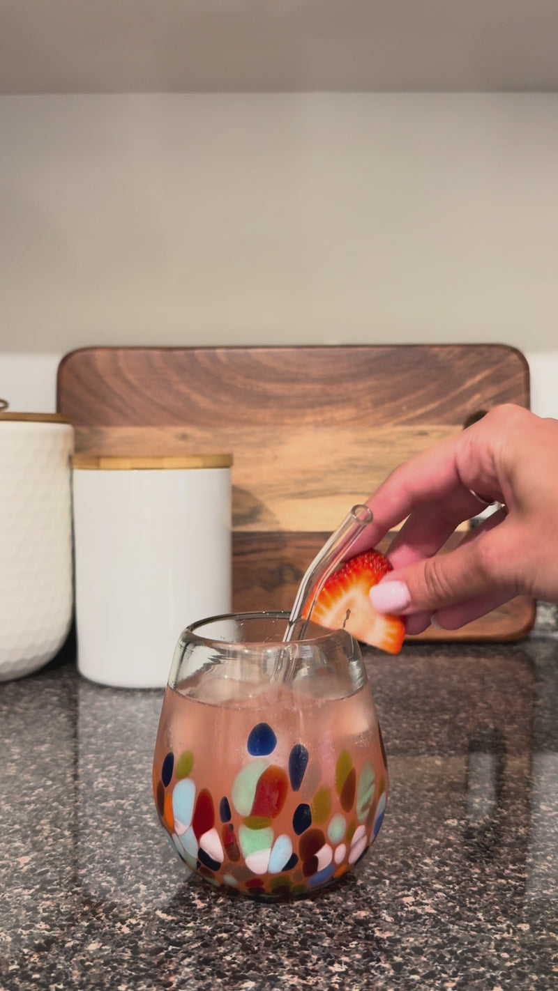 Finished Strawberry Sunset Mocktail served over ice in a colorful glass with a glass straw and fresh strawberry garnish.