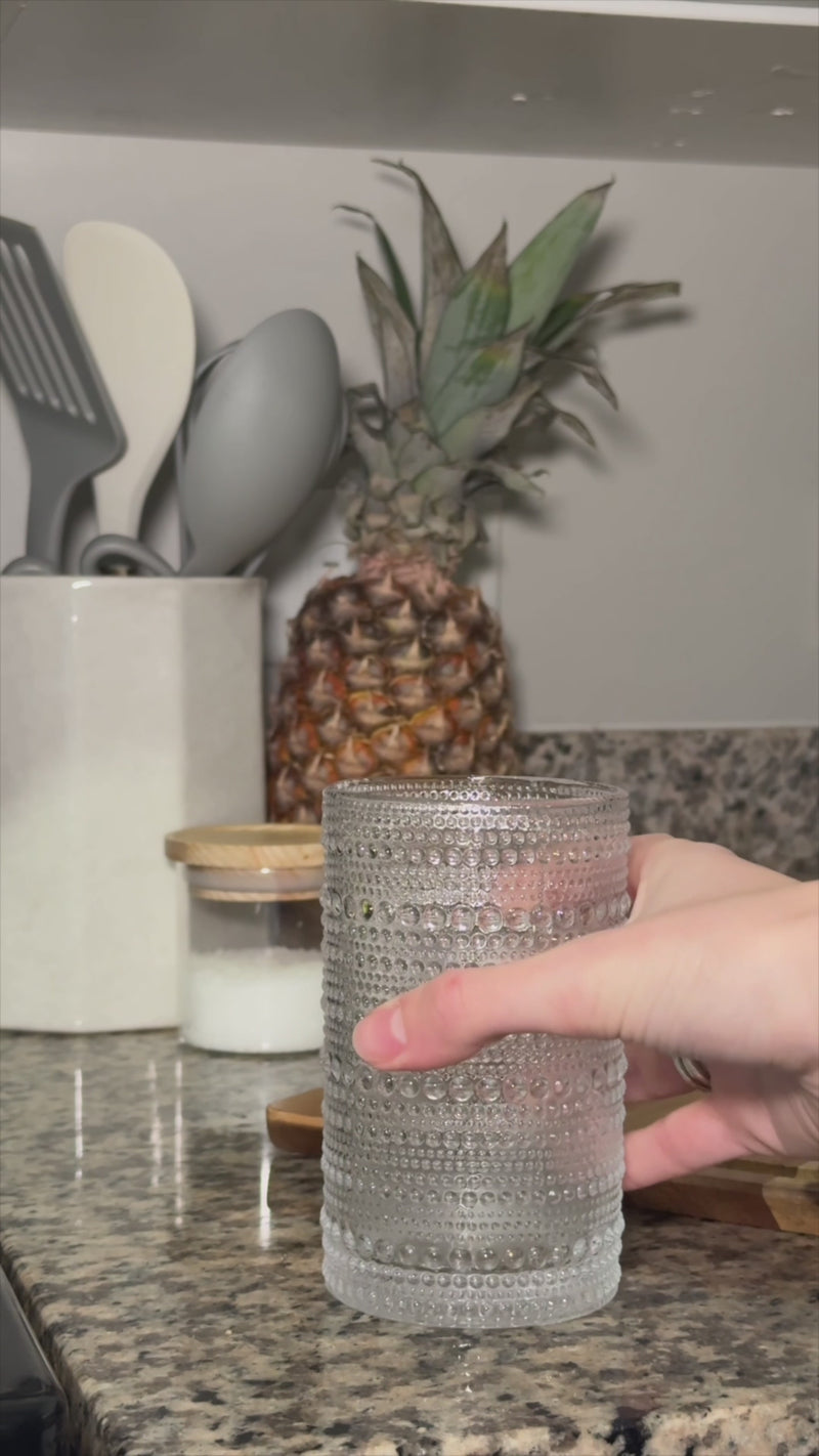 Tropical Garden Cooler being strained into a textured glass filled with fresh ice, finished with a mint garnish and ready to sip.