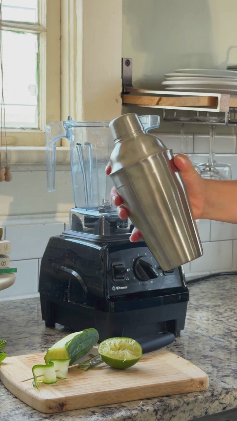 Ice, non-alcoholic prosecco, and club soda being added to a blender with the muddled mint and lime mixture before blending into a frozen slushy drink.