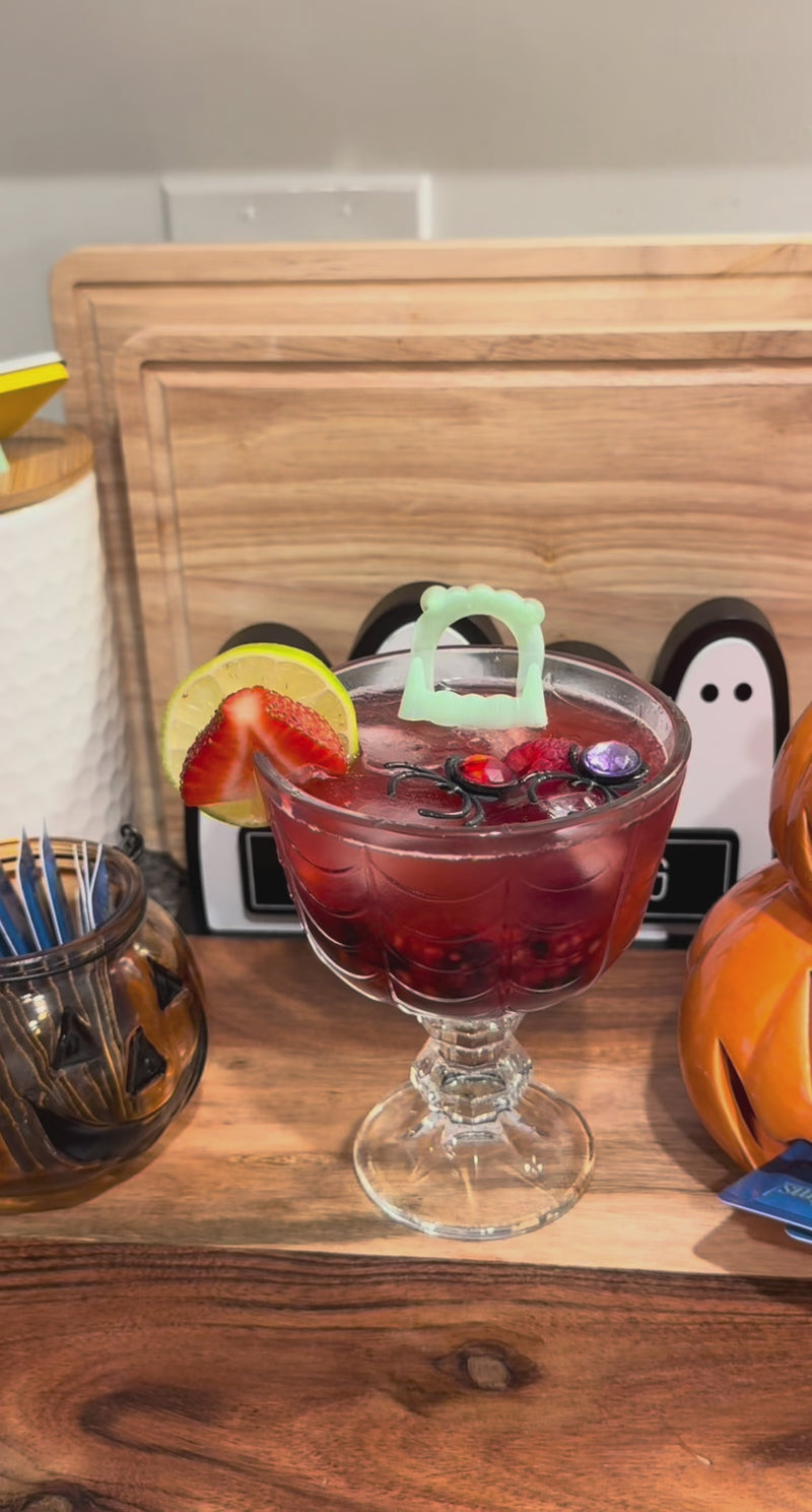 Triple Berry Spritz garnished with fresh berries and spooky Halloween decorations before serving.