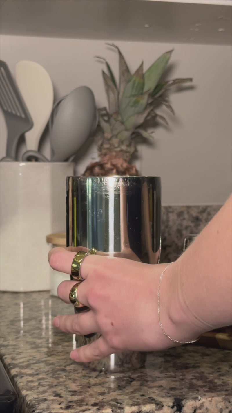 Cocktail shaker on a kitchen counter as pineapple juice, coconut water, fresh mint, and Ginger Lime Wims Pocket-Tonic™ are added over ice for a tropical drink mix.